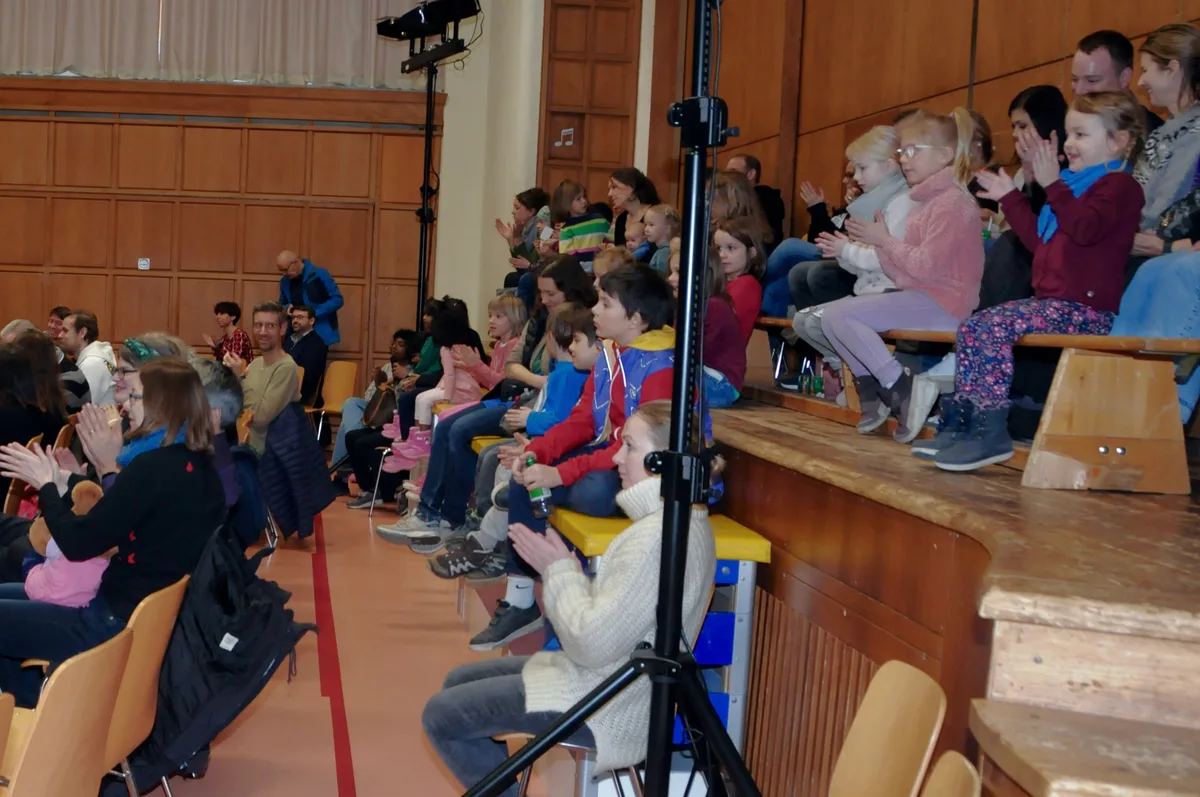 Man sieht Kinder und erwachsene Zuschauer applaudieren.